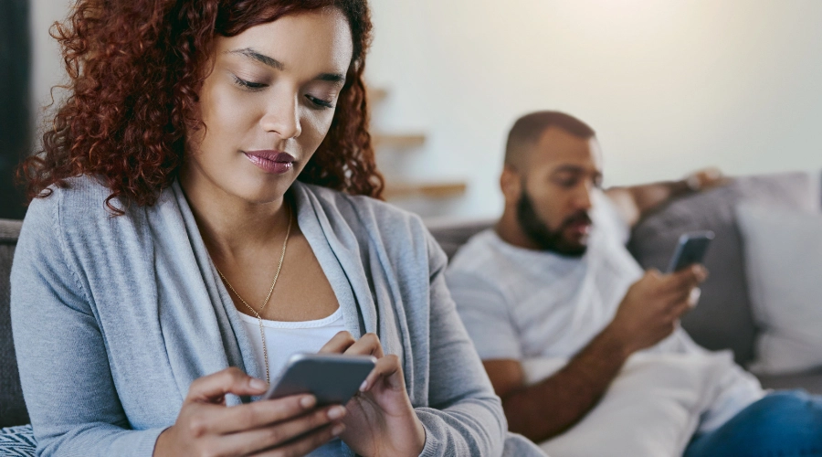 lady using her phone with a man using his own phone in the background