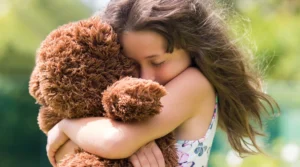 girl hugging toy bear